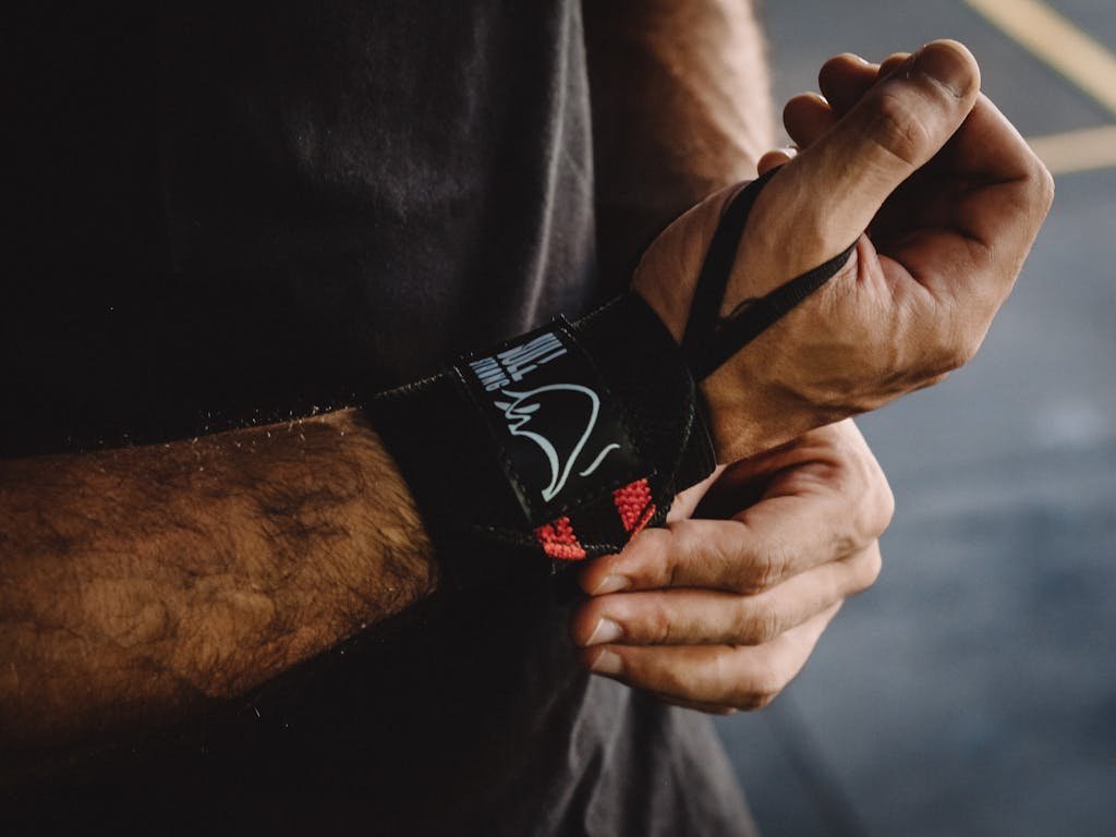 Close-up shot of a man adjusting a wrist strap, highlighting support and strength.