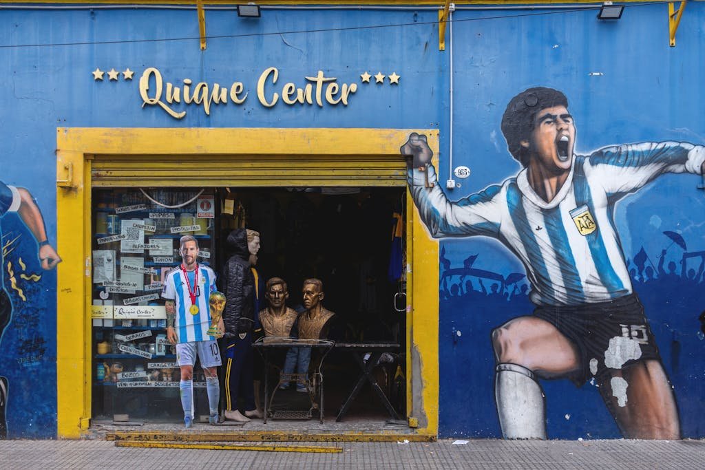 Vibrant storefront in La Boca featuring murals of football legends Maradona and Messi.