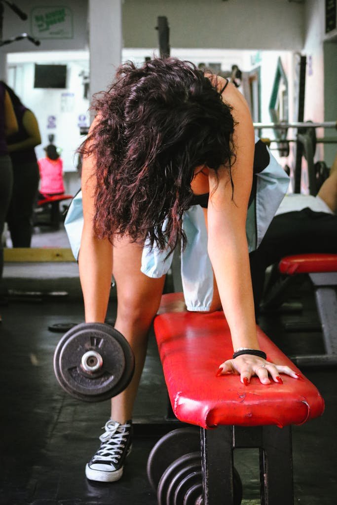 Woman exercising with dumbbell in gym, focusing on strength training and fitness.