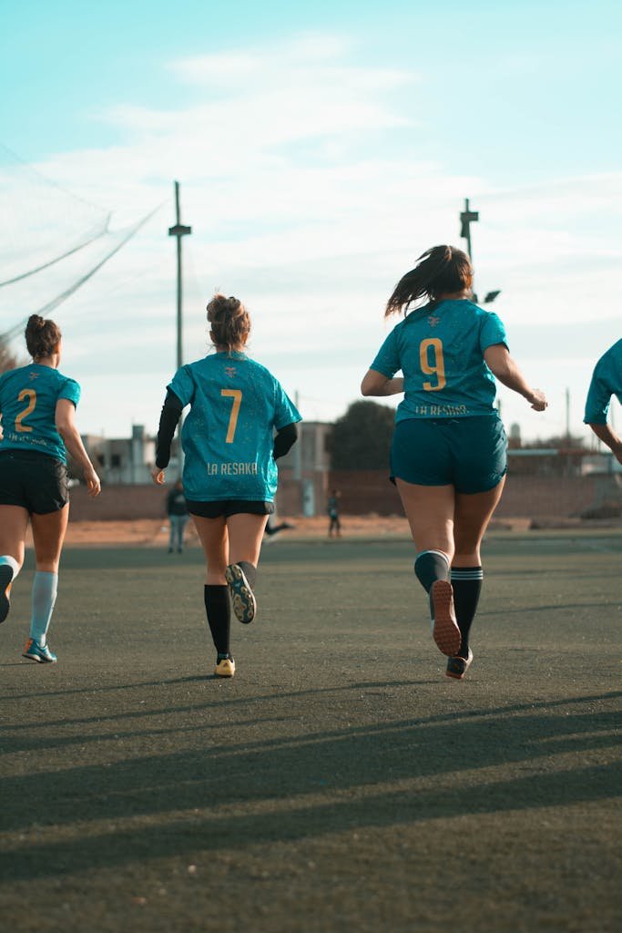 Women soccer team in action on the field during daylight.