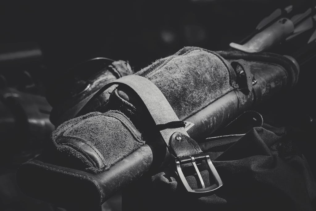 Detailed black and white image of a leather archery quiver with buckle, emphasizing texture and craftsmanship.