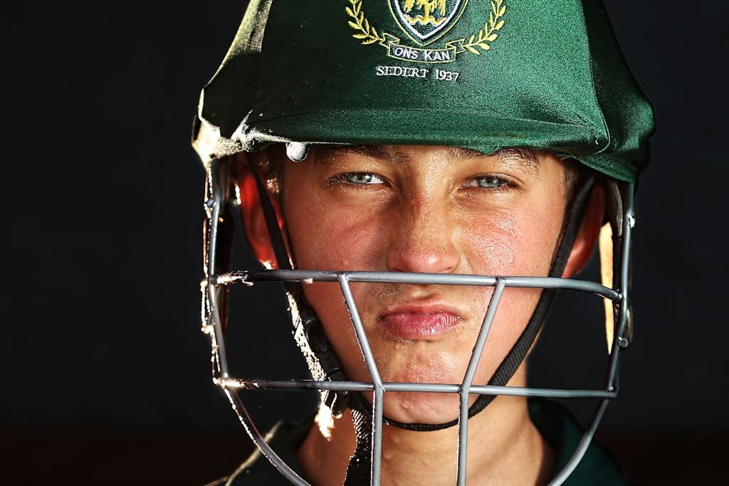 Focused young cricketer wearing a green helmet, preparing for the game.