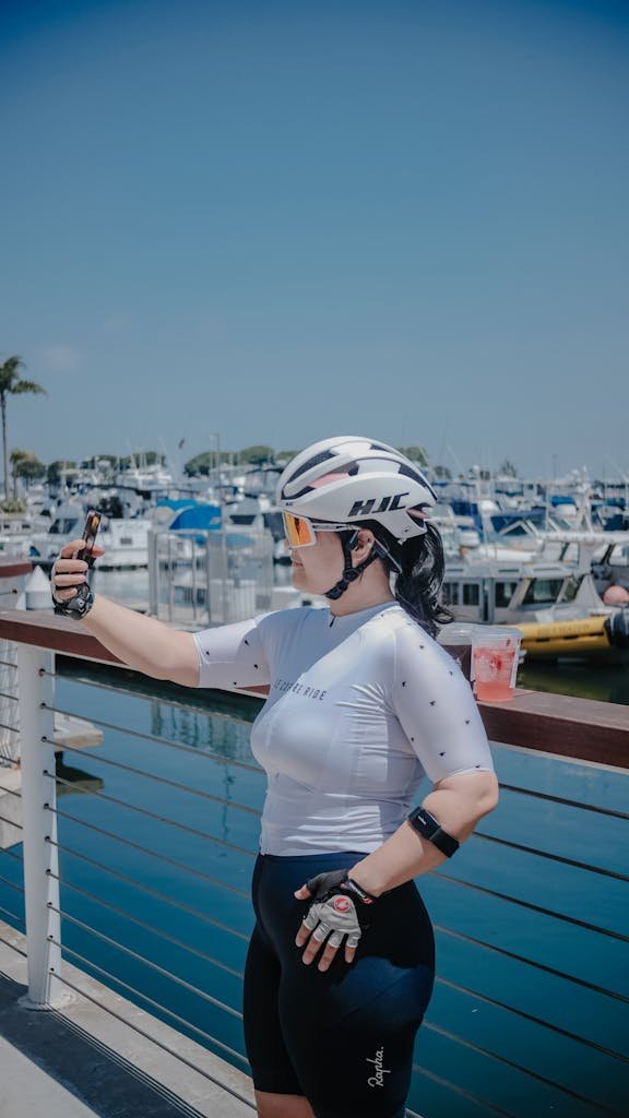 Sportswoman taking selfie near marina while cycling, showcasing active lifestyle.