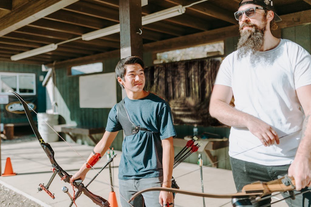 Two men practicing archery outdoors, focusing on technique and form.