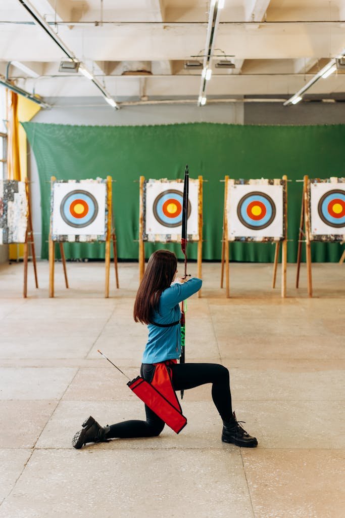 Woman practicing archery indoors, aiming at multiple targets with focus and precision.