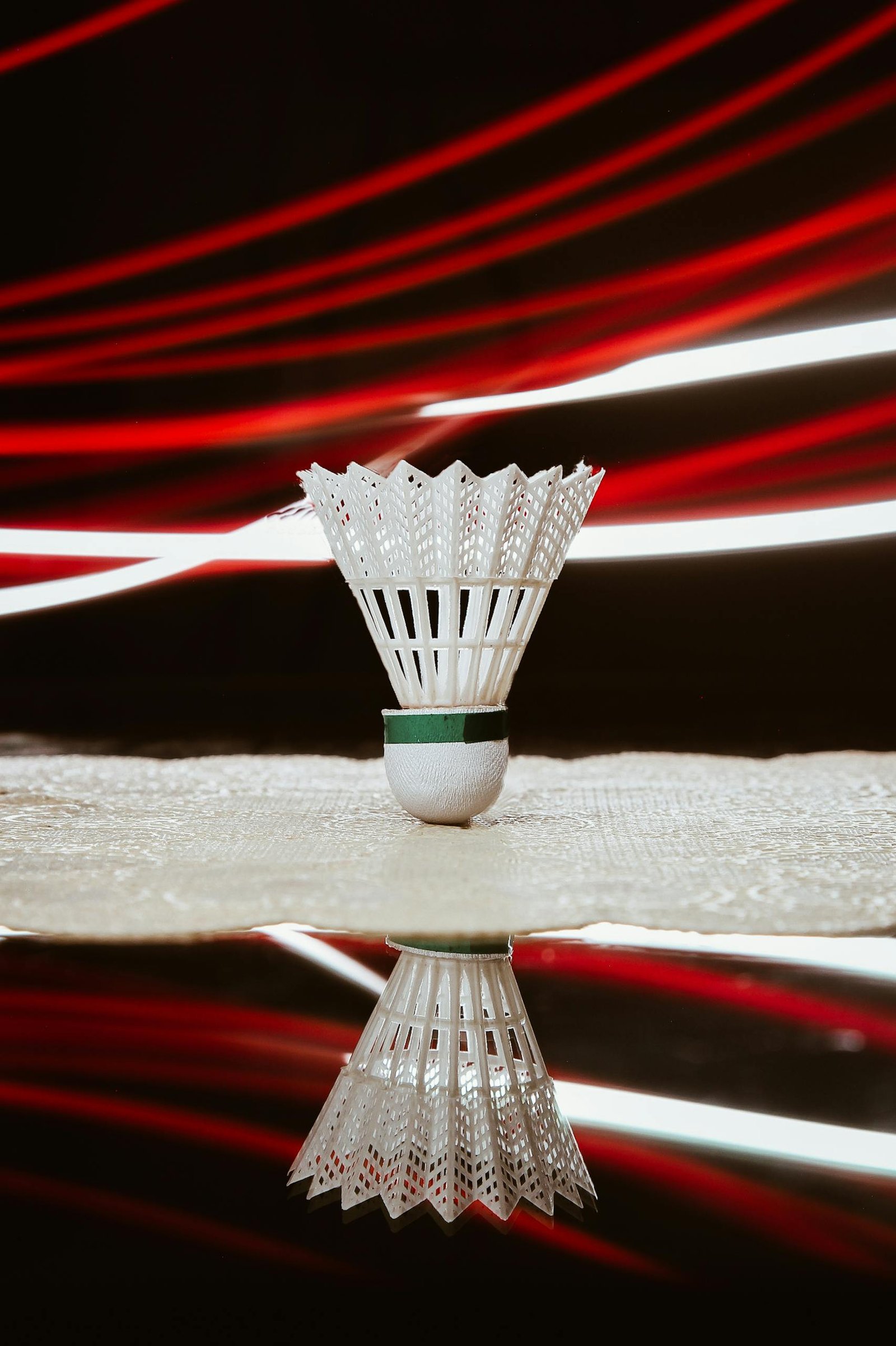 A badminton shuttlecock with dynamic light trails creates a vibrant sports-themed composition.