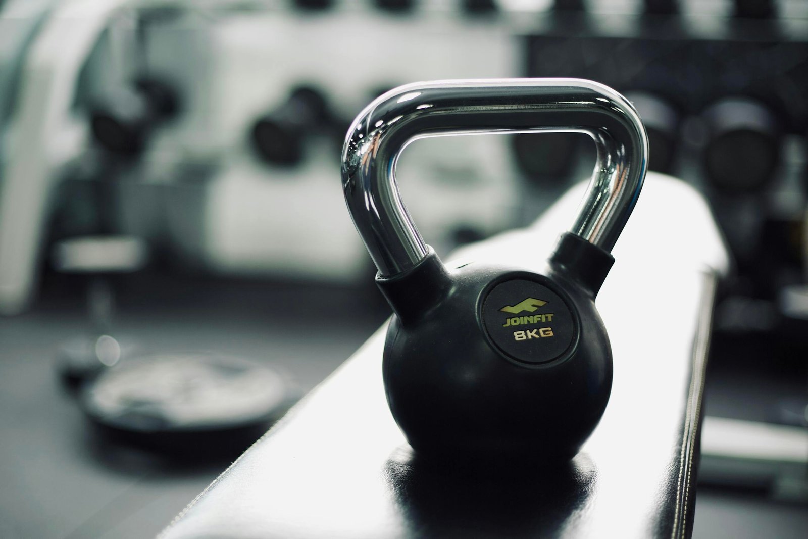 Black kettlebell on gym bench highlighting fitness and strength training equipment.