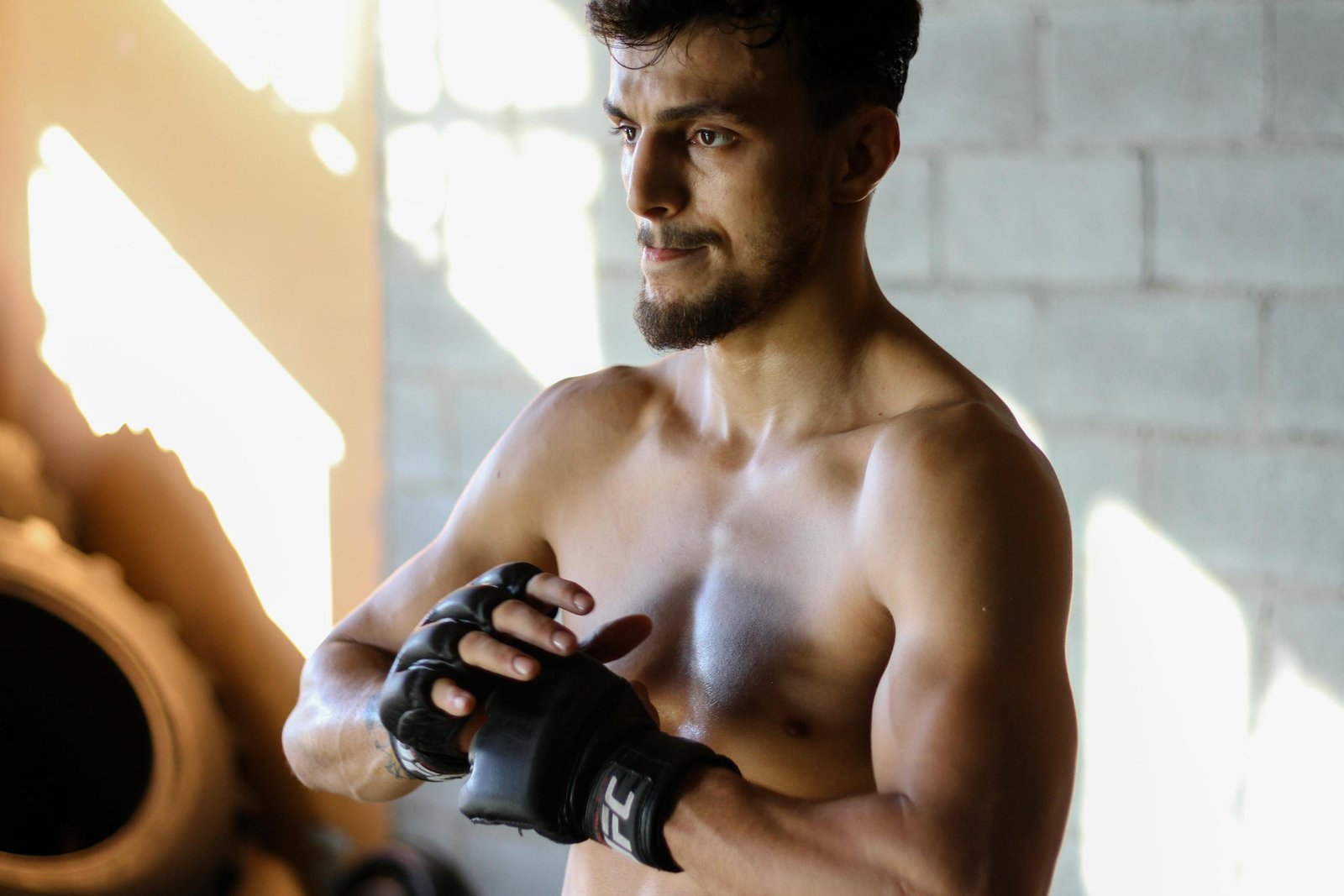 Shirtless man with gym gloves getting ready for an intense workout indoors.