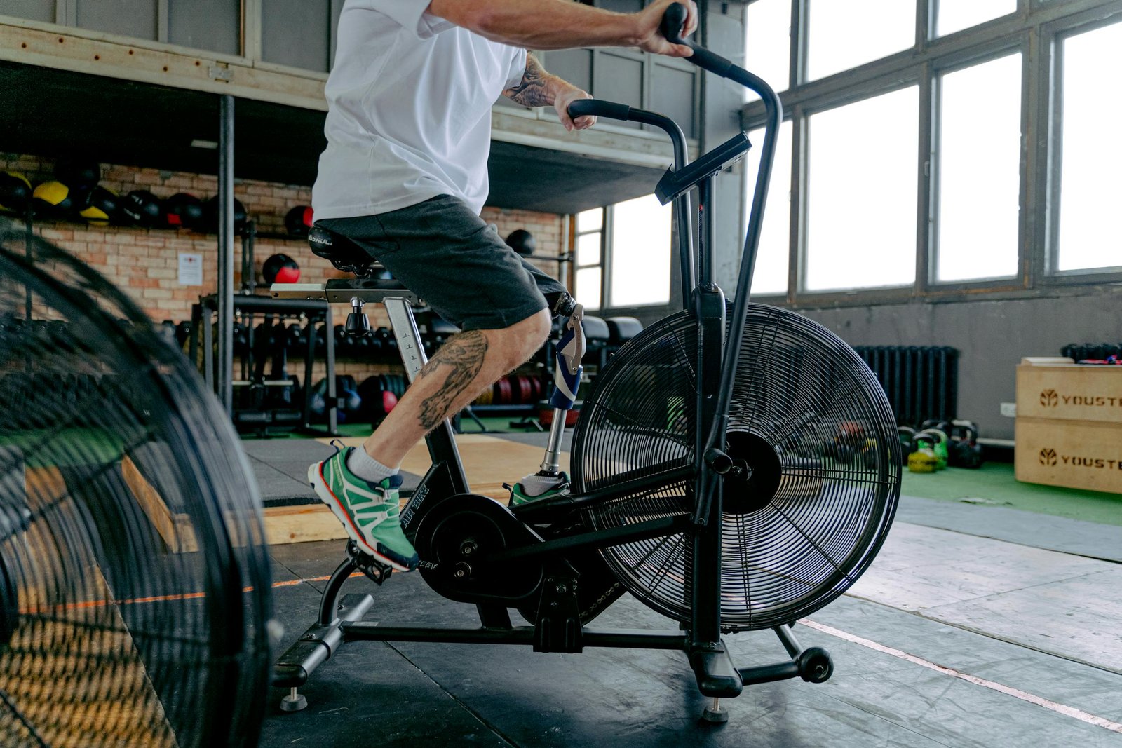 A determined man with a prosthetic leg working out on a stationary bike in a gym environment.