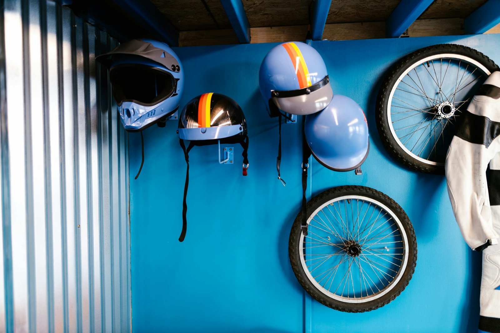 Colorful helmets and bicycle tires hung on a blue wall, showcasing a cycling theme.