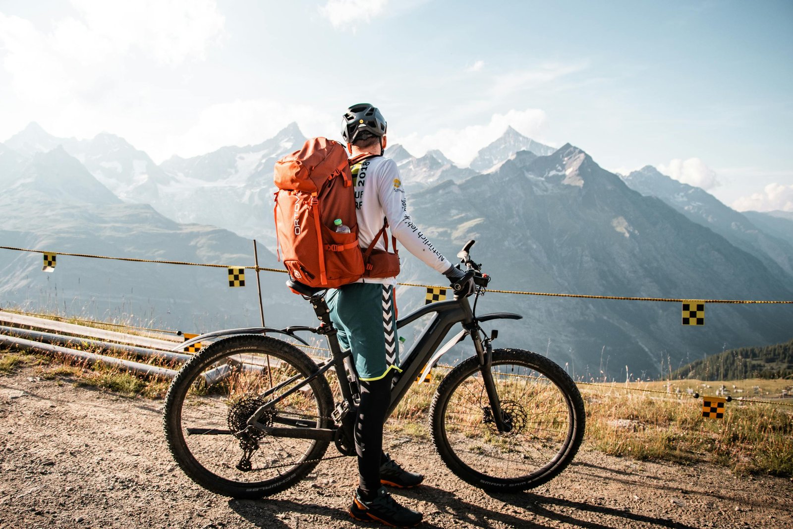 Cyclist with backpack enjoying a scenic mountain view in Saas-Fee, Switzerland.