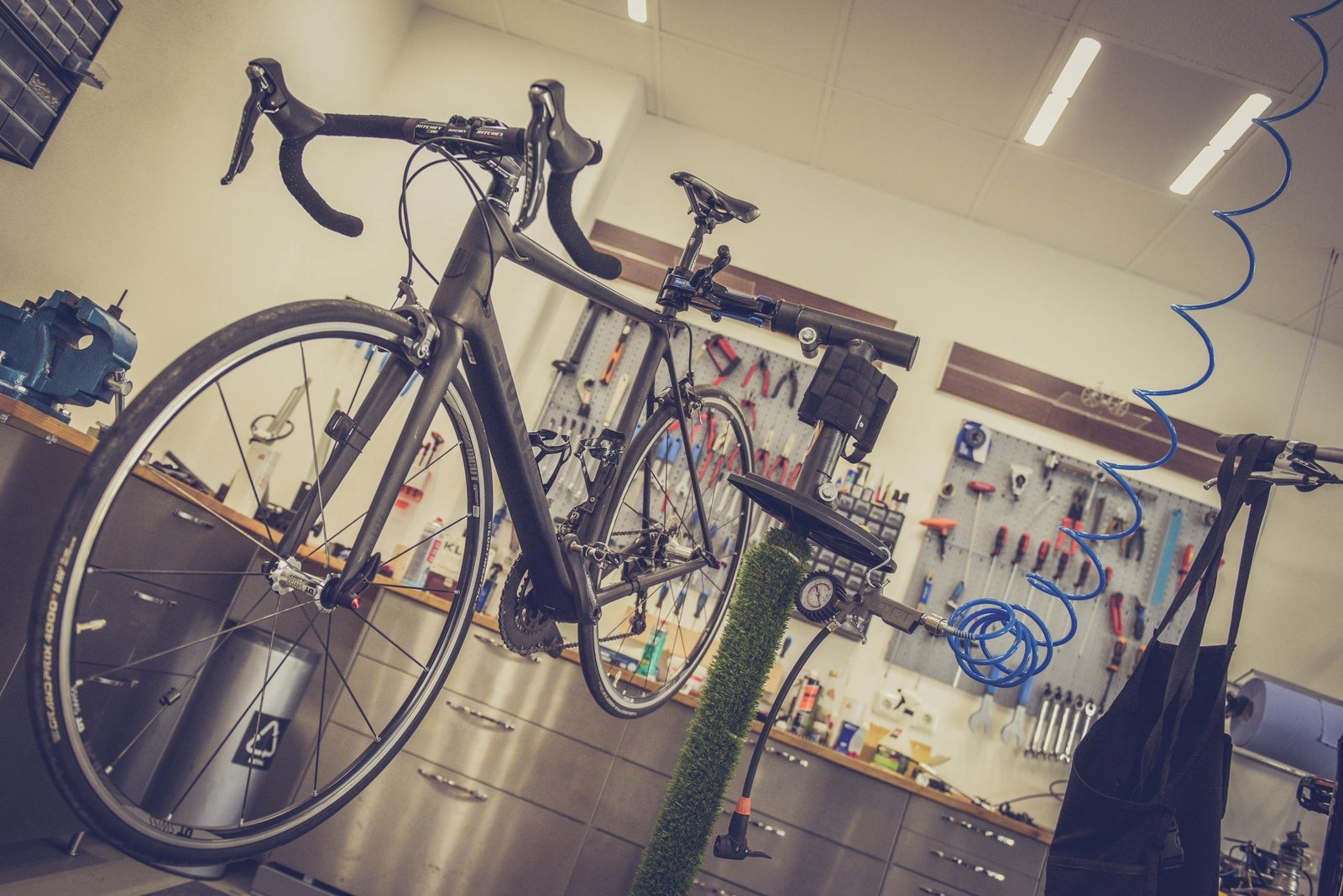 Detailed view of a bicycle being repaired in a modern workshop with tools and equipment.